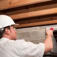 Termite inspection technician checking a basement wall and framing for termite activity in Staten Island, NY